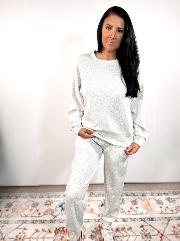 Woman wearing a white sweatshirt and pants set on a neutral background