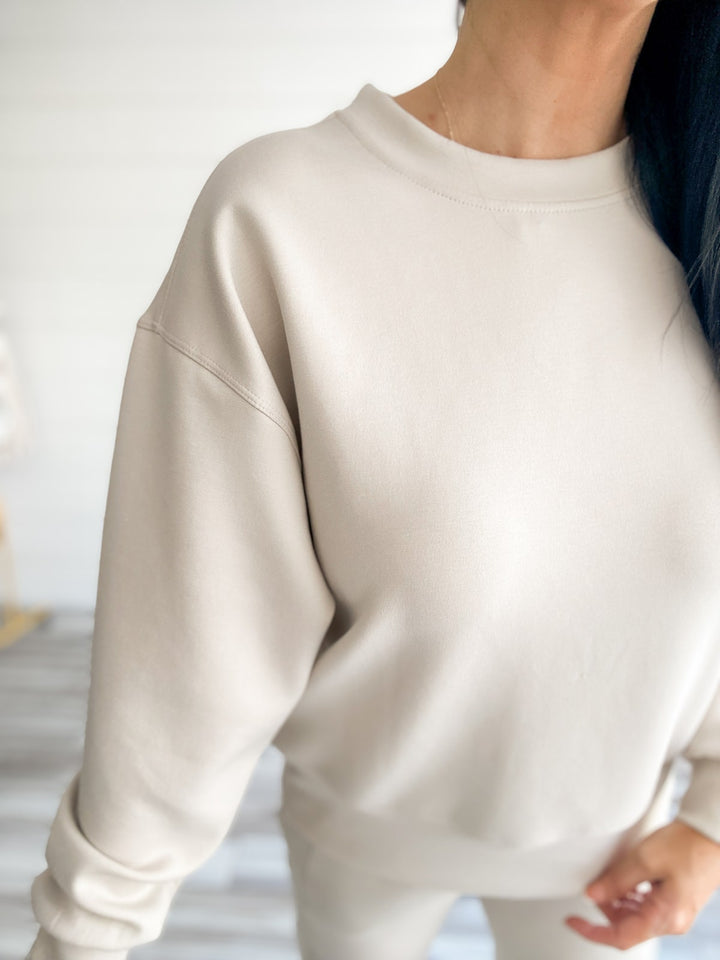 Beige sweatshirt worn by a person with a blurred background
