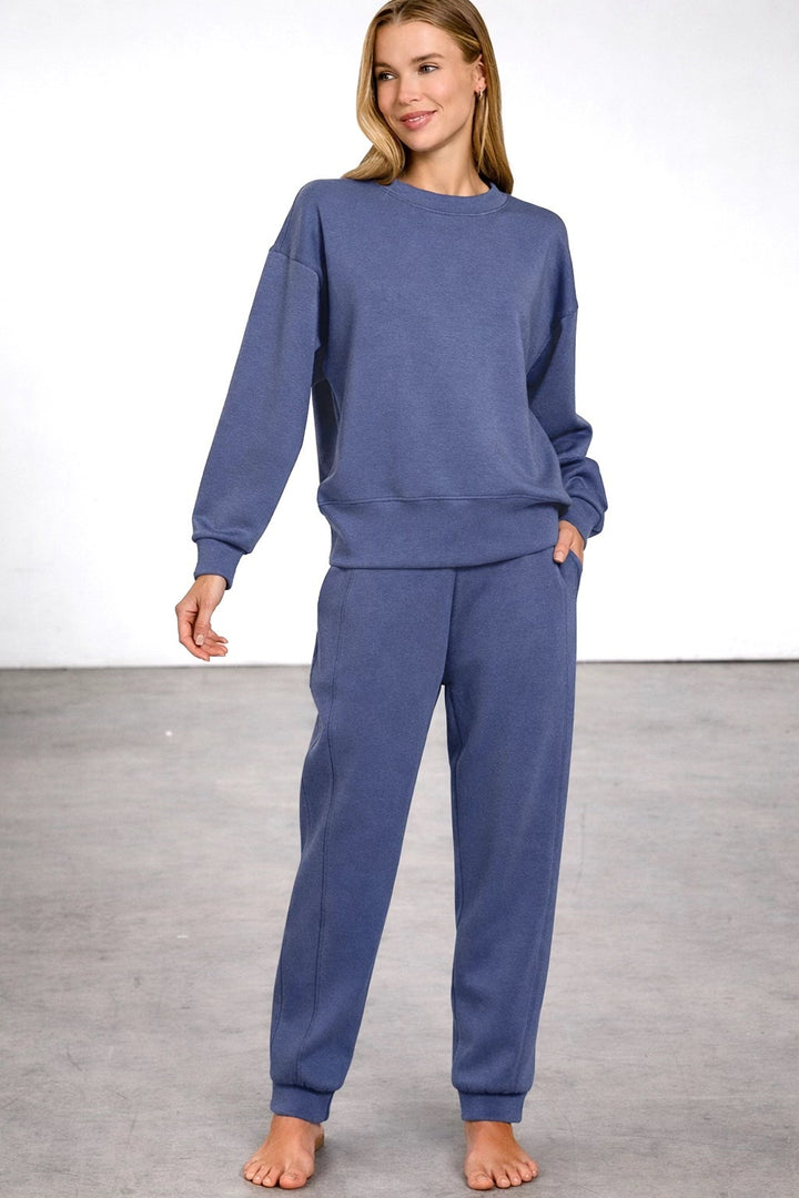 Woman wearing a blue sweatshirt and pants set on a plain background